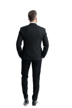 Rear view of elegant man walking with hands in pockets