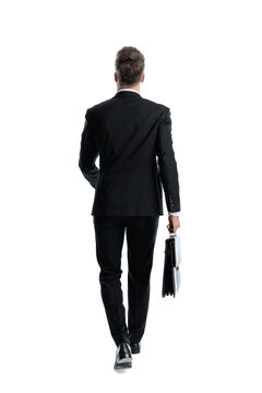 Back view of professional man walking holding briefcase