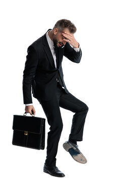 Side view of stressed man holding briefcase touching forehead