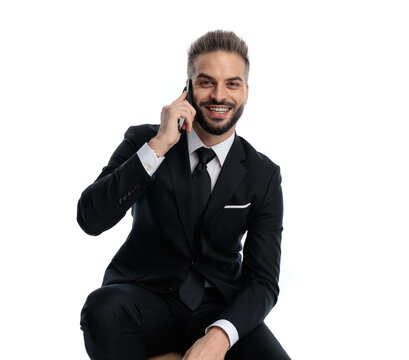 Happy man sitting and talking on phone while smiling