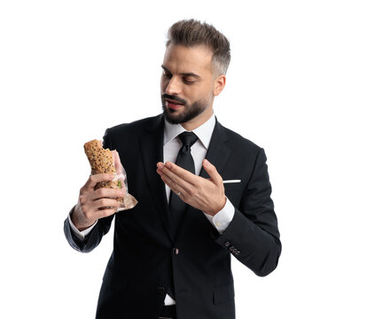 Curious formal man gesturing at half eaten sandwich