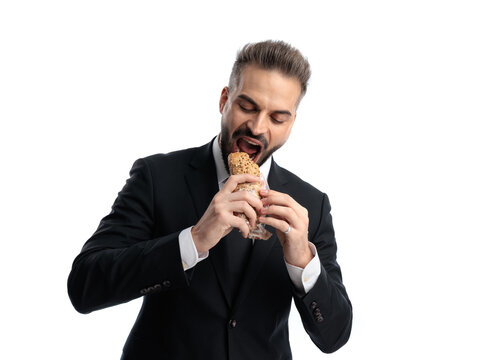 Hungry elegant man biting into a large sandwich