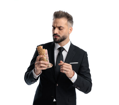 Serious stylish man examining half eaten sandwich