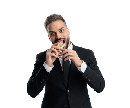 Greedy man eating a sandwich and looking forward