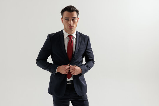 Elegant man adjusting suit jacket and looking forward