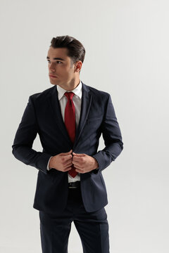 Confident man adjusting suit jacket and looking to the side