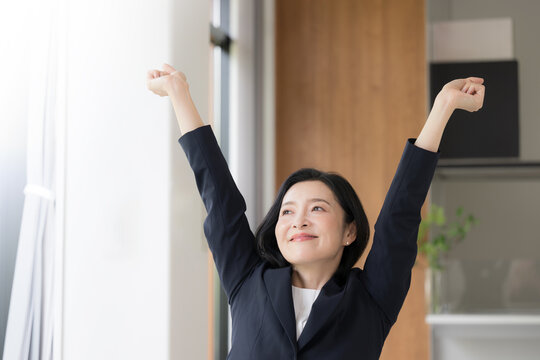 仕事の合間に肩こりのストレッチをする女性会社員、オフィスでリフレッシュするミドル世代のビジネスウーマン 健康経営のイメージ