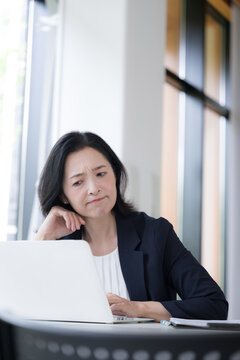 パソコンを見ながら仕事に悩む女性会社員、オフィスで考え込むビジネスウーマンの仕事のストレスや悩み