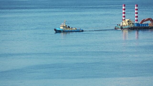 Tugboat towing a construction barge on blue sea, Hakodate, Japan, 2026.09.10.