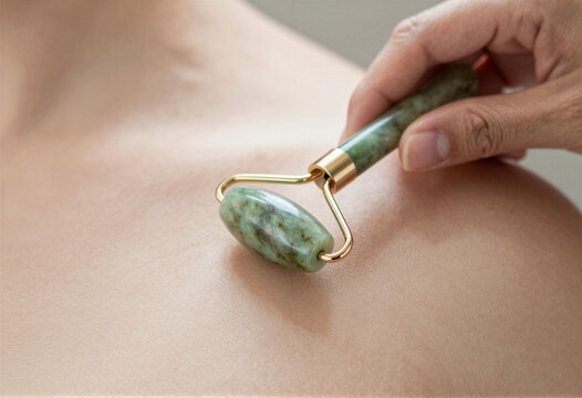A hand using a jade roller on the skin, macro, beauty tool
