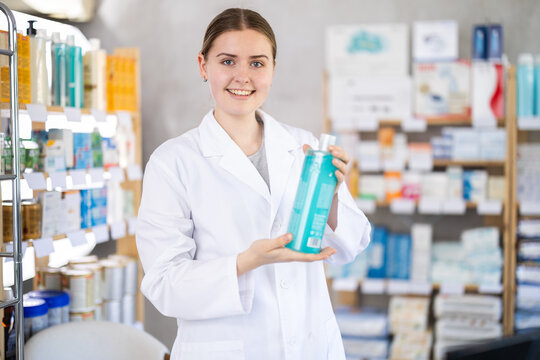 Young female pharmacist offering shampoo
