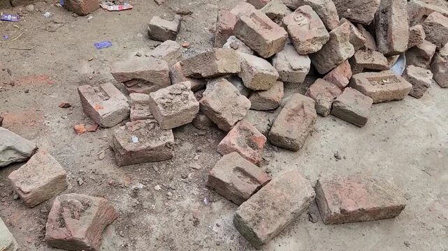 Bricks scattered across the dusty ground at a construction site represent raw building materials awaiting masonry work for structural development in an ongoing urban project.