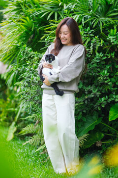 Vertical portrait of a woman holding a black and white colors cat in the garden