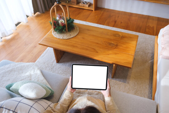 Top view mockup image of a woman holding tablet with blank desktop white screen at home