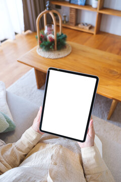 Top view mockup image of a woman holding tablet with blank desktop white screen at home