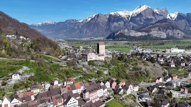 palas wing sargans castle bergfried tower hilltop crest old town colorful rooftops valley railway backdrop rugged snowcapped mountain range rhine valley switzerland aerial orbit drone footage