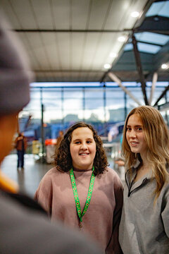Two young women listening and talking with another passenger inside a busy metro station