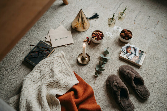 Cozy hygge lifestyle flat lay on carpet, winter home decor with candle and slippers, warm aesthetic morning scene