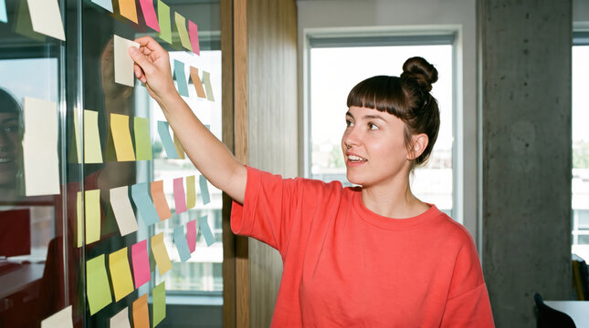 Person sticking a blank note onto a glass wall