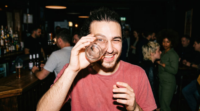 Smiling man hold empty glass at crowded bar party