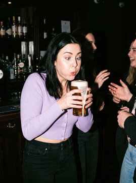 Woman blow foam from beer glass at bar