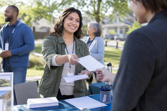 Volunteer offering an information leaflet at a community table