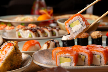 Salmon avocado sushi roll held by chopsticks japanese culinary arts © Игорь Соколов