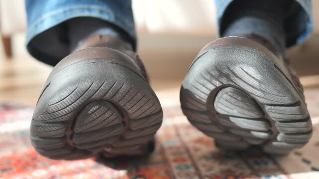 Close up cinematic footage of an elderly man standing on a patterned carpet wearing comfortable brown leather shoes with textured soles