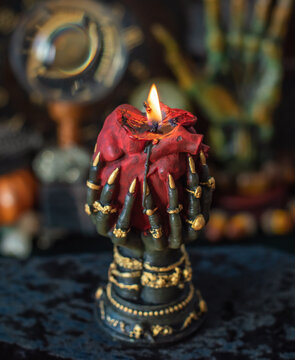 Burning heart candle held by witch hands on magical altar for love spells, cleansing negative energy and romantic rituals 