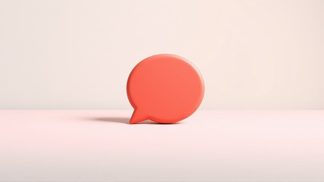 Coral speech bubble rests upon pale surface. Minimalist studio shot, soft shadows, simple composition. Focus on communication concept.