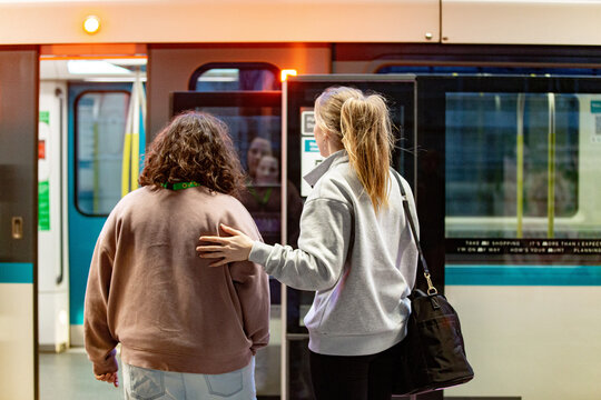 Two young women standing on a train platform to get into the train