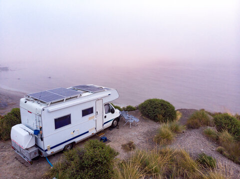 Caravan with solar panels on roof on coast, Spain. Aerial view.