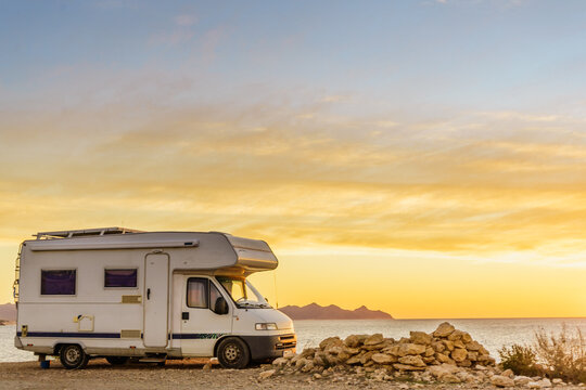 Warm sunrise view at the beach with a camper van parked along the sea shore