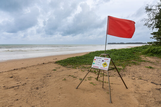 Red flag alert on beach front signaling danger and no swimming is allowed in Phuket beach, Thailand. Overcast sky in photo.