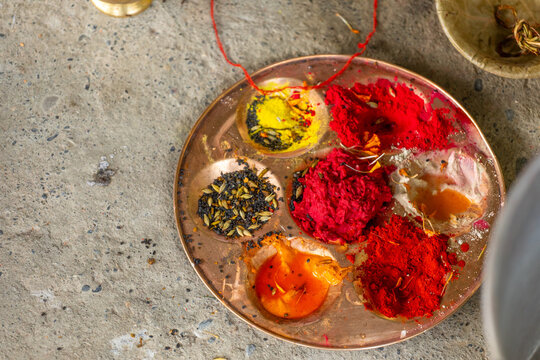 View of a traditional puja plate with vibrant red vermilion, yellow turmeric powder, and seeds used during a ceremony at Bangladi Shiva Temple in Pokhara, Gandaki Province, Nepal.