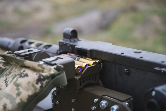 Close up view of a heavy machine gun with brass ammunition cartridges loaded into the feeding mechanism. 