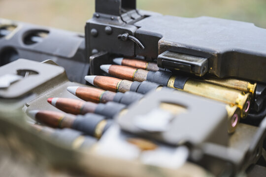 Detailed close up of linked large caliber ammunition loaded into the feed mechanism of a heavy machine gun.