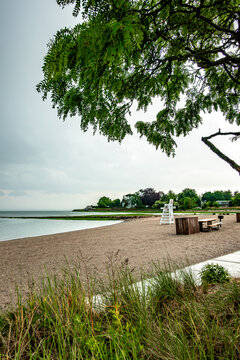 Overcast day at a quiet coastal beach with a lifeguard chair and framing tree along the New England shore