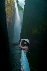 Side profile portrait of woman in conical hat beside canyon waterfall, Muong Hum, Lao Cai, Vietnam © nhat.photograph