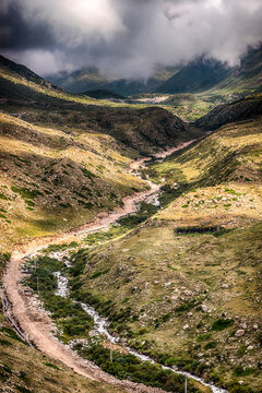 Mountain valley and winding stream under cloudy sky Kyrgyzstan