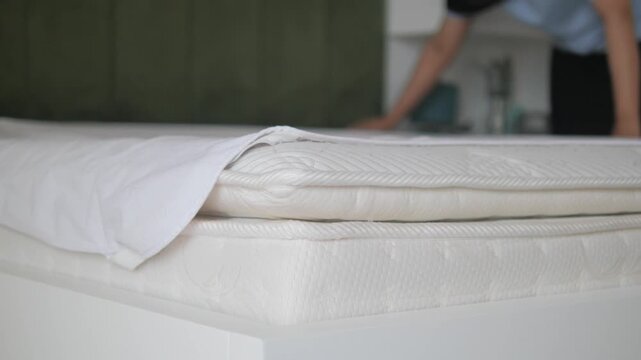 A blurred figure of woman setting up a comfortable white mattress and pillow for good sleep and morning routine