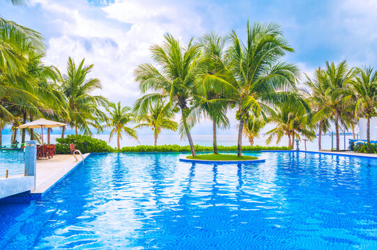 pool on the beach by the sea in a luxury resort. A pool on the ocean coast with palm trees in the tropics in Asia