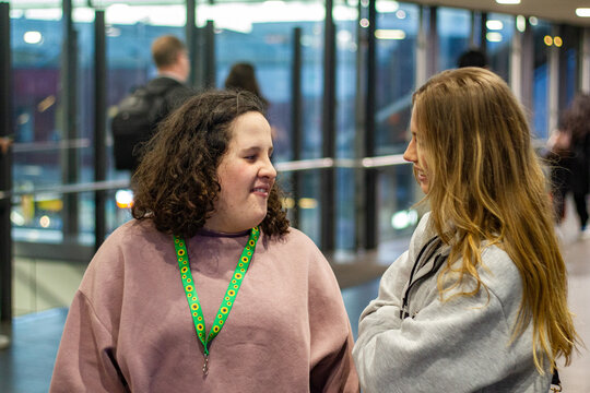 Two young women standing inside the modern, glass-walled train station