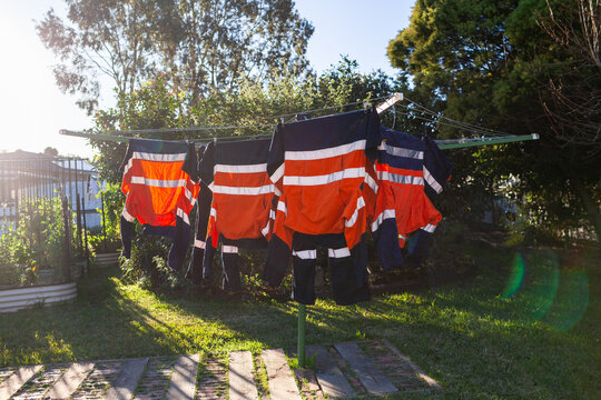 Sun flare behind washing line in Australian backyard with high vis workwear hung on clothesline