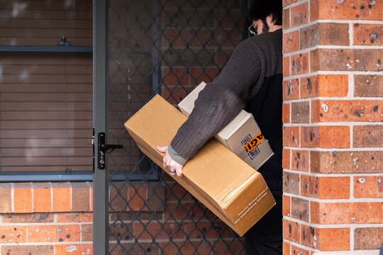 Man picking up boxes from outside door of home from online delivery orders