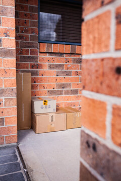 Cardboard boxes piled outside door of house from online home delivery orders