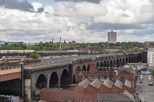 View of the historic brick railway viaduct stretching across the urban landscape with industrial buildings and a cloudy sky in Birmingham, England, United Kingdom.