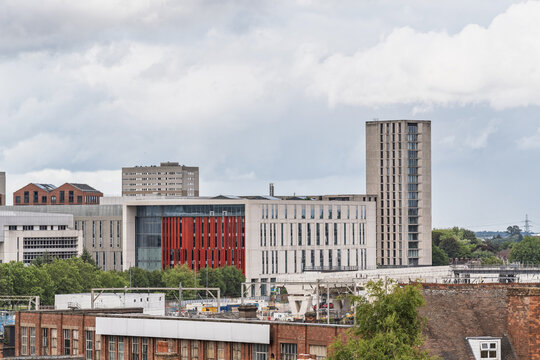 View of modern and historic buildings in the city center, including a prominent red-accented office building and a tall concrete tower in Birmingham, England, United Kingdom.