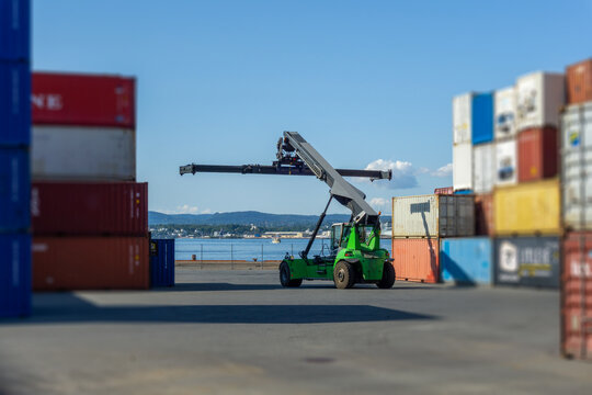 Reach stacker moving containers in cargo port logistics
