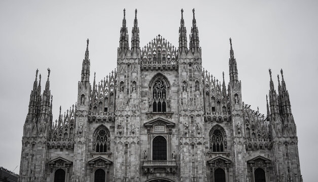 Duomo di Milano facade, covered in pale Candoglia marble with Gothic arches, statues, pinnacles, ornate tracery, and towering spires.
